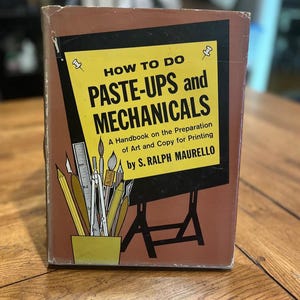 May include: A vintage book titled "HOW TO DO PASTE-UPS and MECHANICALS" by S. Ralph Maurello. The cover is brown with a yellow rectangle containing the title and a drawing of art supplies. The book is a handbook on art and copy preparation for printing.