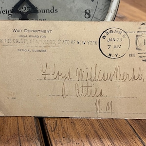 May include: A vintage postcard from the War Department, addressed to Floyd William Merkle. The card is stamped with a January 23, 1918 postmark from N.Y. The postcard is tan with black text and handwriting.