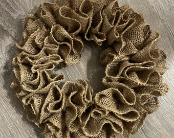 May include: A brown burlap wreath with a ruffled texture. The wreath is made of burlap fabric and is a popular choice for rustic home decor.