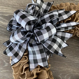 May include: A black and white checkered bow with black trim, tied on a brown burlap wreath.