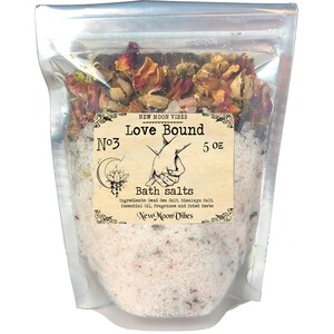 Peut inclure: Un sac en plastique transparent rempli de sels de bain blancs et de p&eacute;tales de rose s&eacute;ch&eacute;s. Le sac porte une &eacute;tiquette sur laquelle est inscrit "N&deg;3 Love Bound 5 oz Bath salts Ingredients: Dead Sea Salt, Himalayan Salt, Essential Oil, Fragrance and Dried Herbs New Moon Vibes"