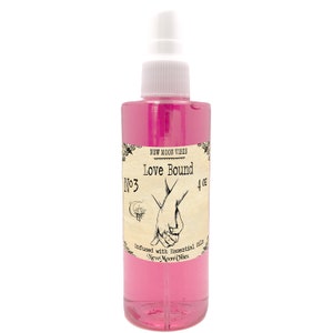 May include: A pink glass bottle with a white spray nozzle. The label reads "New Moon Vibes Love Bound No3 4 oz Infused with Essential Oils New Moon Vibes".