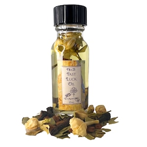 May include: A small glass bottle with a black cap filled with a yellow liquid and dried flowers. The label reads "No.21 Fast Luck Oil" and "New Moon Oils 15mL".