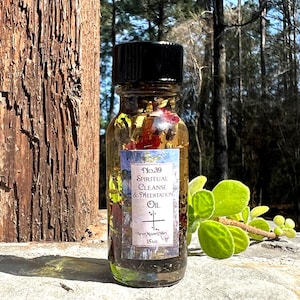 May include: A small glass bottle with a black cap filled with a clear oil and herbs. The label reads "No.39 Spiritual Cleanse & Meditation Oil" with a cross symbol and "New Moon Divas 15mL".