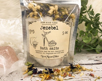 Peut inclure: Une pochette argentée avec une étiquette qui indique "New Moon Vibes Jezebel No. 5 5 oz Bath salts Ingredients: Dead Sea Salt, Himalaya Salt Essential Oil, Fragrance and Dried Herbs New Moon Vibes". La pochette contient un mélange d'herbes séchées et de sels de bain.