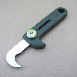May include: A green plastic utility knife with a hook blade and a safety lock. The blade is partially extended and the handle has a small, round, metal button.