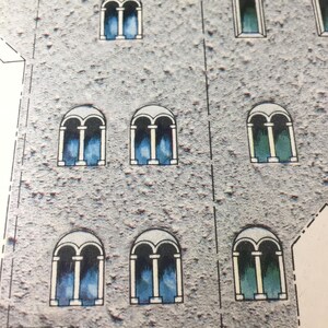 May include: A close-up of a building facade with multiple arched windows. The windows have a white frame and are filled with a blue and green stained glass design.
