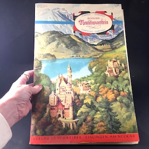 May include: A vintage postcard featuring a colorful illustration of Neuschwanstein Castle, a fairytale-like castle in Germany. The postcard is printed in German and English and includes the text "CASTLE SCHLOSS CASTILLO Neuschwanstein CASTELO CHATEAU" and "VERLAG J.F. SCHREIBER ESSLINGEN AM NECKAR".