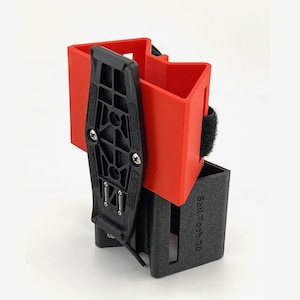 May include: A black and red 3D-printed accessory with a rectangular base and a red, angular top section. A black mounting bracket is attached with screws. The text "Sell Tech 3D" is printed on the side.