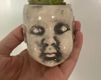 Mini vaso per piante a forma di testa di bambola.