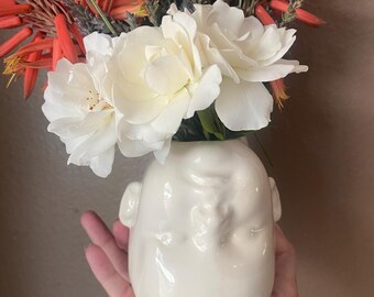 Creepy white doll upside down flower  vase.
