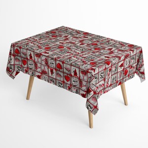 Könnte beinhalten: Eine rechteckige Tischdecke mit weißem Hintergrund und einem sich wiederholenden Muster aus roten Herzen, Weihnachtsbäumen und Geschenken. Die Tischdecke ist über einen Holztisch mit vier Beinen gelegt.