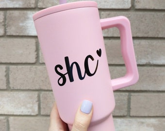 May include: A pink travel mug with a black handle and a black vinyl decal that says "she" with a small heart.