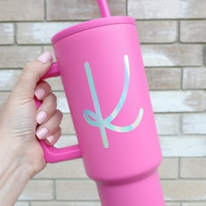 May include: Pink stainless steel tumbler with a handle and a holographic letter K sticker.