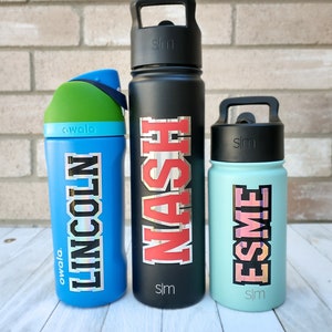 May include: Three water bottles with personalized names. The bottles are black, blue, and light blue. The names are "Nash", "Lincoln", and "Esme".