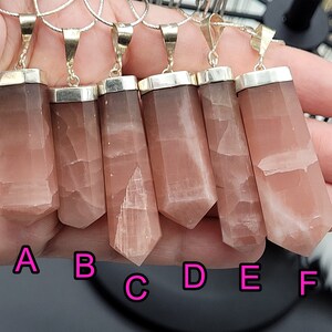 May include: Six pink and white gemstone pendants with silver settings. The pendants are labeled A through F.