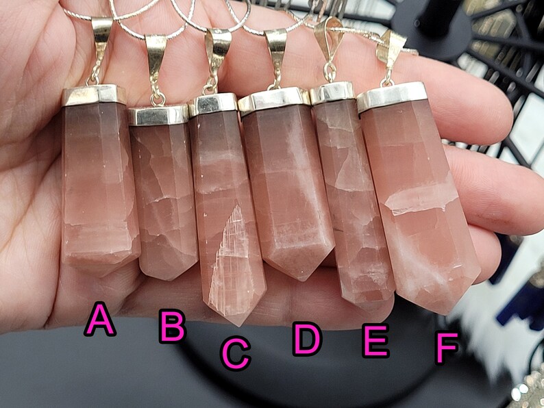 May include: Six pink and white gemstone pendants with silver settings. The pendants are labeled A through F.