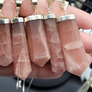 May include: Six pink and white gemstone pendants with silver settings. The pendants are in the shape of a long, thin rectangle with a pointed end.
