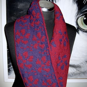 May include: A purple and burgundy crocheted infinity scarf with a geometric pattern.