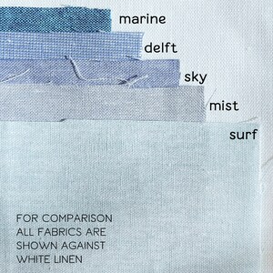 May include: Five fabric swatches in shades of blue, from dark teal to light blue, labeled "marine", "delft", "sky", "mist", and "surf".  The text "FOR COMPARISON ALL FABRICS ARE SHOWN AGAINST WHITE LINEN" is at the bottom of the image.