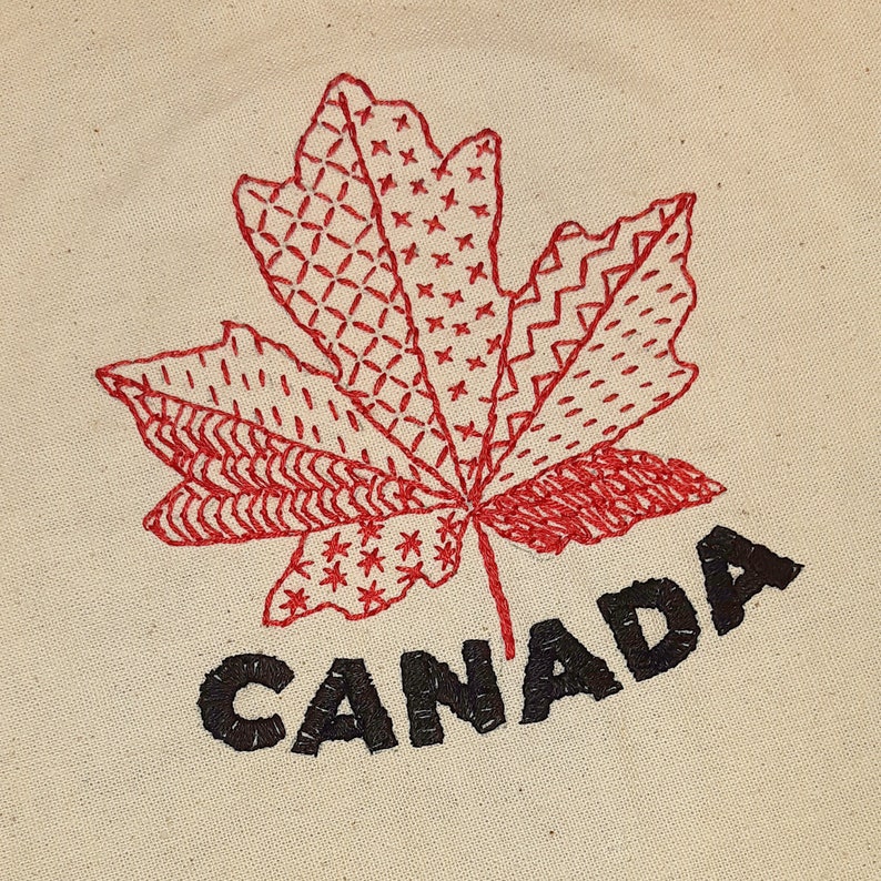May include: Red embroidered maple leaf with a stitched pattern and the word "CANADA" in black lettering.