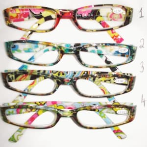 Puede incluir: Cuatro pares de gafas de lectura con coloridos estampados florales. Cada par tiene una graduación diferente, indicada en las lentes. Las monturas son rectangulares con patillas estampadas a juego.