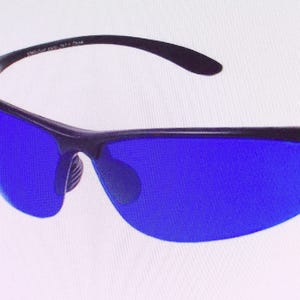 Può includere: Un paio di occhiali da sole neri con lenti blu. Gli occhiali hanno un design avvolgente e un look elegante e moderno.