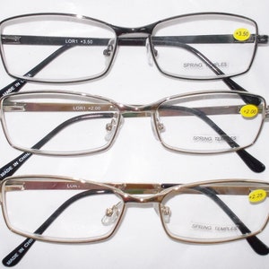 May include: Three pairs of reading glasses with spring temples. The top pair is black with silver accents and says "LOR1 +3.50". The middle pair is silver with black accents and says "LOR1 +2.00". The bottom pair is gold with black accents and says "LOR1 +2.25".