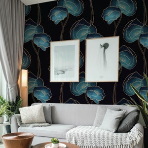May include: A living room with a dark blue and gold floral wallpaper, a gray couch with two pillows, a throw blanket, and two framed pictures on the wall.