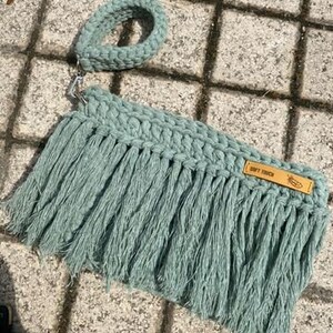 May include: A light green crocheted bag with fringe and a brown leather tag that says "Soft Touch".