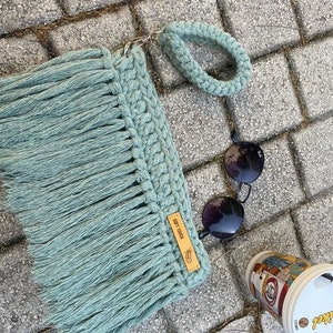 May include: A light green crocheted bag with a fringe and a brown leather tag that says "Soft Touch".