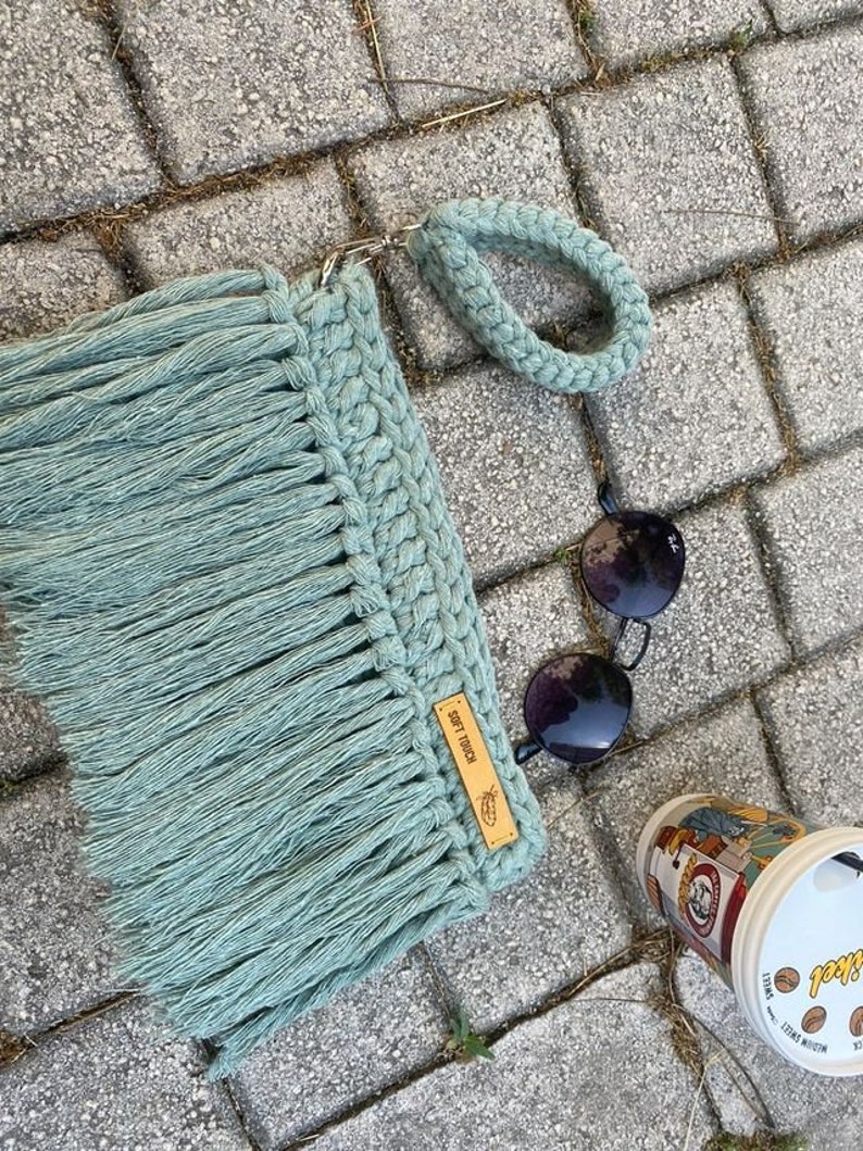 May include: A light green crocheted bag with a fringe and a brown leather tag that says "Soft Touch".