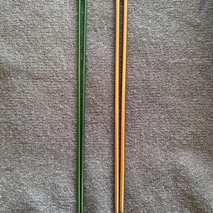 May include: Two pairs of knitting needles. One pair is a metallic green color, and the other is a metallic gold color. Both pairs have a rounded, gold-colored top. The needles are long and slender, designed for crafting.