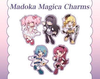 May include: Five anime-style character charms arranged on a white background with a scalloped purple border. The text Madoka Magica Charms is printed at the top. Each character features distinct outfits and hair colors including pink, black, yellow, blue, and red.