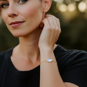Woman wearing a beautiful moonstone link bracelet with gold box chain and bezel.