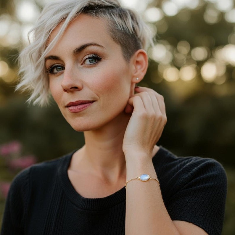 Woman wearing a beautiful moonstone link bracelet with gold box chain and bezel.