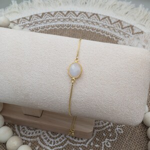 Oval moonstone link is attached on both long ends to gold box chain on fully adjustable chain.