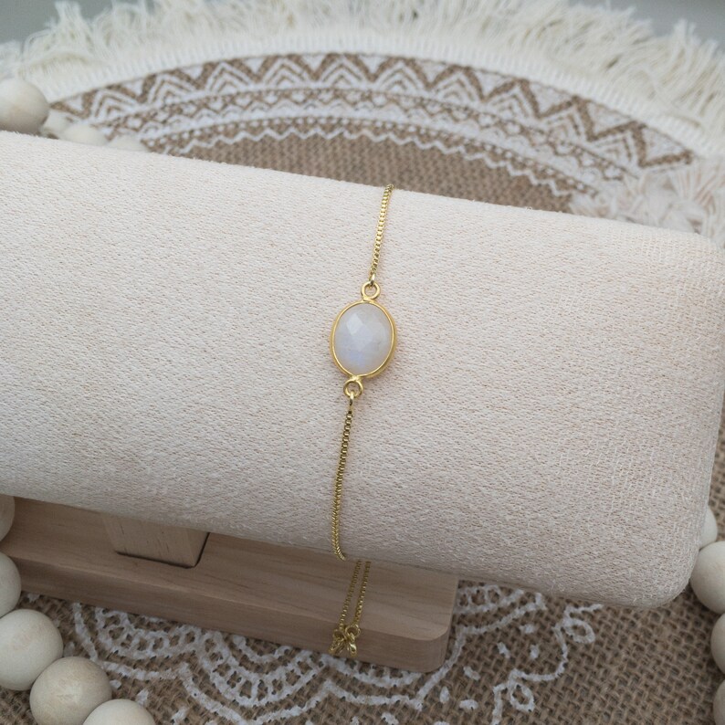 Oval moonstone link is attached on both long ends to gold box chain on fully adjustable chain.