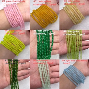 Peut inclure: Neuf brins de perles de calcédoine teintes dans différentes couleurs, notamment rose, jaune, vert et bleu. Chaque brin est étiqueté avec un numéro et une description de la couleur.