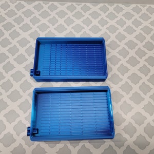 Puede incluir: Dos bandejas de pl&aacute;stico azul con un patr&oacute;n de rejilla en la parte inferior. Las bandejas est&aacute;n vac&iacute;as y parecen ser para organizar art&iacute;culos peque&ntilde;os.