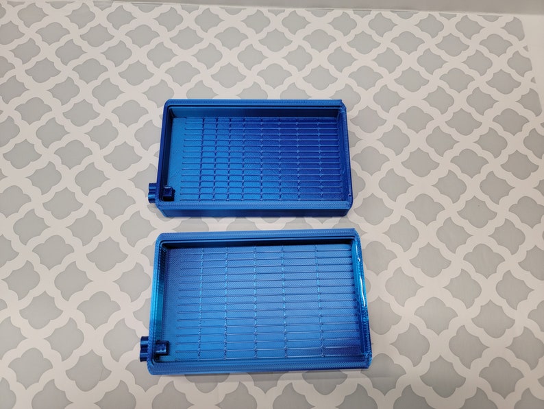 Puede incluir: Dos bandejas de pl&aacute;stico azul con un patr&oacute;n de rejilla en la parte inferior. Las bandejas est&aacute;n vac&iacute;as y parecen ser para organizar art&iacute;culos peque&ntilde;os.