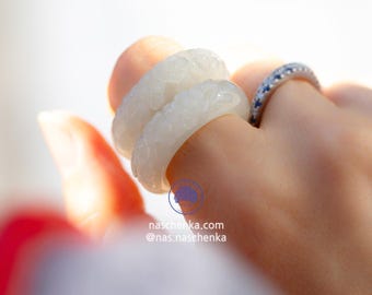 May include: Two white jade rings with intricate floral carvings. The rings are stacked on top of each other and are worn on a finger.