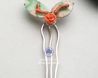 Könnte beinhalten: Ein silberner Haarkamm mit floralem Design. Der Kamm hat eine Korallenrose, Korallenäste und grün-weiße Blätter. Der Kamm hat drei Zinken und den Text naschenku.com und @nas.as.herna.