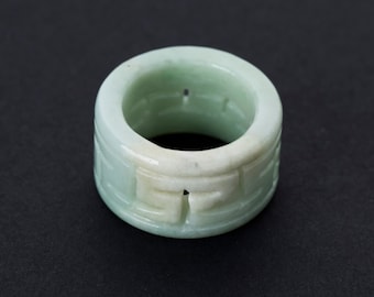 Könnte beinhalten: Ein grüner Jade-Ring mit aufwendigen Schnitzereien. Der Ring ist aus glattem, poliertem Jade gefertigt und hat ein filigranes Design.