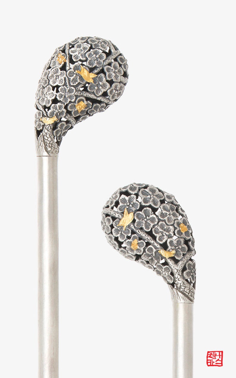 May include: Two silver walking sticks with ornate handles. The handles are made of silver and are decorated with a floral design. The flowers are made of silver and are accented with gold. The sticks are a traditional Japanese design.