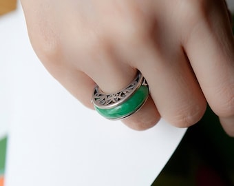 May include: A silver ring with a green jade stone set in a delicate filigree design.