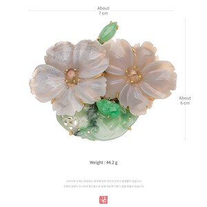 以下が含まれることがあります： 翡翠と白瑪瑙で作られた繊細な花のブローチ。ブローチは、金色のアクセントが施された2つの白瑪瑙の花と、翡翠の葉のデザインが特徴です。ブローチの長さは約7cm、幅は約6cm、重さは44.2グラムです。
