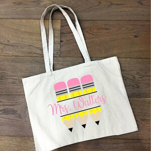 May include: A white canvas tote bag with three yellow pencils with pink erasers and the text "Mrs. Walters" in pink.