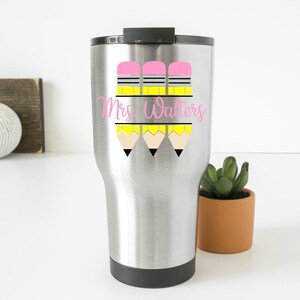 May include: A stainless steel travel mug with a pink and yellow pencil design and the text "Mrs. Walters".