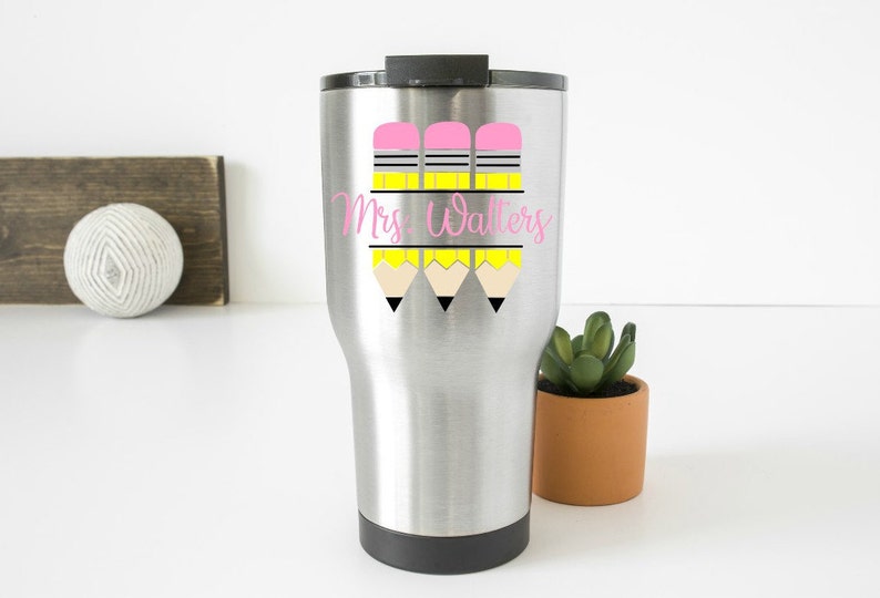 May include: A stainless steel travel mug with a pink and yellow pencil design and the text "Mrs. Walters".